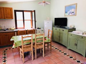 cocina con mesa, sillas y nevera en Villetta al Mare circondata dal Verde (Carloforte - Spalmatore) en Carloforte
