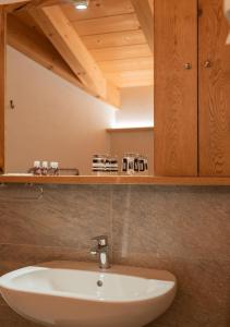 a bathroom with a white sink and a wooden cabinet at Pista Stelvio Loft Lumière in Bormio +44 photos