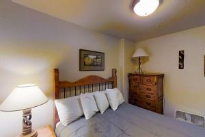 a bedroom with a bed with a lamp and a dresser at Romance at Riverbends' Snowflake Lift in Breckenridge
