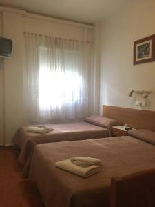 2 Betten in einem Zimmer mit einem Fenster und Handtüchern darauf in der Unterkunft PENSION MIRAFLORES in Saragossa