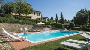 una piscina con sillas y una casa en Cottage il Borraccio, en Barberino di Val d'Elsa