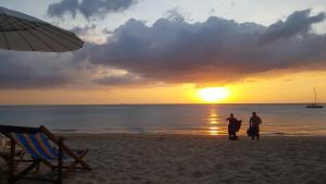 dos personas de pie en la playa viendo la puesta de sol en Home No.9, en Ko Lanta