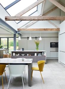 a kitchen with a dining table and yellow chairs at Willow Barn Norfolk Broads B&B in Stokesby