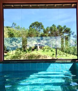 a view of a swimming pool through a window at Chalés na Fazenda Ritmos da Terra in Angelina