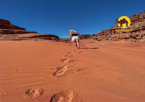 a man walking in the desert with a goat in the background at Wadi Rum Dew in Wadi Rum