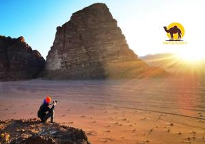 a person sitting on a rock on a beach with a dog at Wadi Rum Dew in Wadi Rum