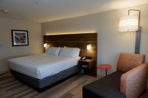 a hotel room with a bed and a chair at Holiday Inn Express & Suites McKinney - Frisco East, an IHG Hotel in McKinney