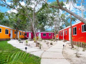 a row of colorful houses with trees and a sidewalk at Colorbox beds and rooms in Tulum