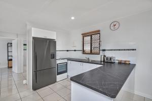 
a kitchen with a refrigerator, stove, sink and microwave at The Red Sparrow 2 in Cairns
