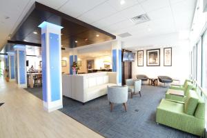 a lobby with green chairs and a dining room at Holiday Inn Express & Suites Chicago North Shore - Niles, an IHG Hotel in Niles