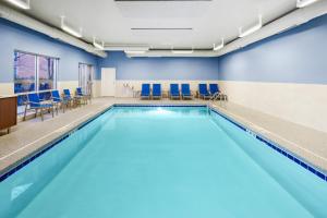 una piscina con sedie blu in un edificio di Holiday Inn Express & Suites Chicago North Shore - Niles, an IHG Hotel a Niles