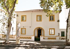une maison blanche avec des arbres devant elle dans l'établissement ZOETIC sustainable rooms, à Évora