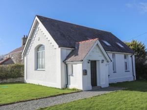 a small white building with a black roof at Capel Hermon in Holyhead