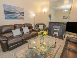 a living room with leather furniture and a fireplace at Preswylfa in Caernarfon
