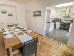 a dining room with a table and a kitchen at Preswylfa in Caernarfon