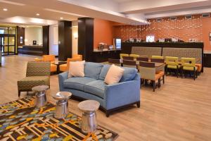 a lobby with a couch and tables and chairs at Holiday Inn Express & Suites Austin South, an IHG Hotel in Austin