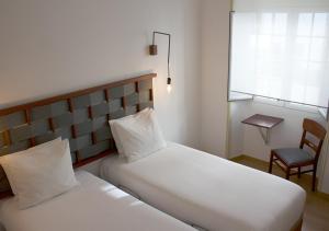 a bedroom with two white beds and a chair at ZOETIC sustainable rooms in Évora
