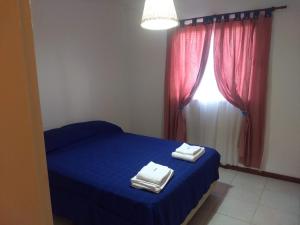 - une chambre avec un lit bleu et 2 serviettes dans l'établissement Departamento Santa Rosa, à Santa Rosa