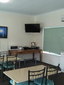 a room with a table, chairs and a television at Sun Valley Motel Biloela in Biloela