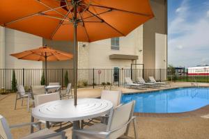tavolo e sedie con ombrelloni e piscina di Holiday Inn Express & Suites Bay City, an IHG Hotel a Bay City