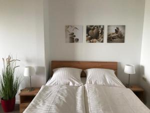 a bedroom with a bed with two lamps and pictures on the wall at Steiner Strandappartements Appartement 205 Seeseite in Stein