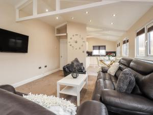 uma sala de estar com um sofá de couro e uma televisão em Sparrows Den Lodge em Winchelsea