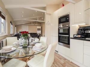 una cucina e una sala da pranzo con tavolo e sedie in vetro di Sparrows Den Lodge a Winchelsea