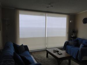 sala de estar con sofá azul y ventana grande en Condominio Arena Maris, en Algarrobo
