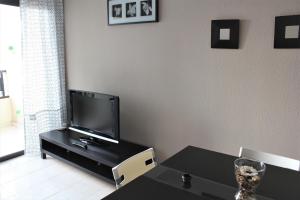 a living room with a tv and a table at Magnífico apartamento Playa Paraíso in Callao Salvaje