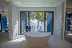 a bath tub sitting in a bathroom next to a window at Sri Panwa Phuket Luxury Pool Villa Hotel - SHA Plus in Panwa Beach
