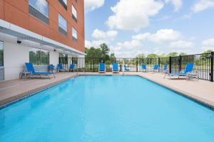 a swimming pool with blue chairs next to a building at Holiday Inn Express & Suites Bryan - College Station, an IHG Hotel in Bryan