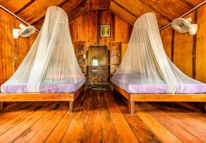 two beds with mosquito nets in a room with wooden floors at White Beach Bungalows in Koh Rong Island