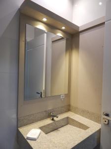 Apto. Novo e decorado. في بومبينهاس: حمام مع حوض ومرآة كبيرة