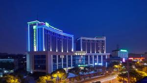 Holiday Inn Express Nantong Downtown, an IHG Hotel في نانتونغ: مبنى كبير عليه علامة في الليل