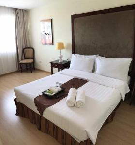 a bedroom with a large bed with two towels on it at The Capital Residence Suites in Bandar Seri Begawan