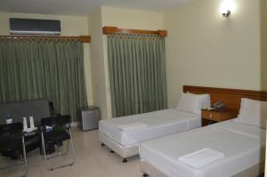 a hotel room with two beds and a table and chairs at Bashati Bay Resort in Cox's Bazar
