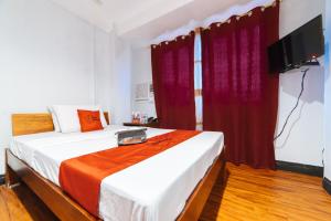 1 dormitorio con 1 cama grande y cortinas rojas en RedDoorz at Nirvana Pension House en Bacolod