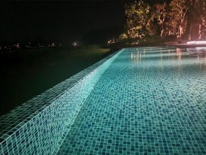a swimming pool at night with blue tiles at Cassia Apartment 1 in Bang Tao Beach