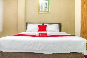 Una cama grande con una almohada roja. en RedDoorz near Plaza Senayan en Yakarta