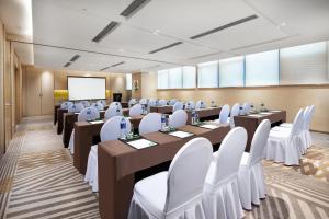 a conference room with tables and chairs and a screen at Holiday Inn & Suites Lanzhou Center, an IHG Hotel in Lanzhou