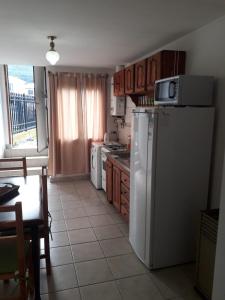 eine Küche mit einem weißen Kühlschrank und einem Tisch in der Unterkunft Ses Hunnica in Ushuaia