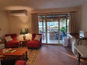 Oaktree Guest House في Narbethong: غرفة معيشة مع كرسيين وأريكة وطاولة