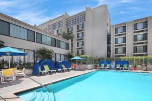 einen Pool mit Stühlen und Sonnenschirmen vor einem Hotel in der Unterkunft Holiday Inn Hotel & Suites Anaheim, an IHG Hotel in Anaheim