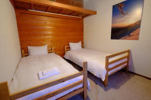 two twin beds in a room with wooden walls at Margo's Garden Farmstay, Kiroro in Akaigawa