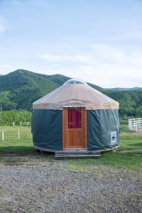 a yurt with a wooden door in a field at Margo's Garden Farmstay, Kiroro in Akaigawa