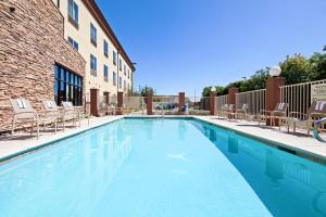 una grande piscina con sedie e un edificio di Holiday Inn Express & Suites Clovis Fresno Area, an IHG Hotel a Clovis