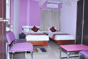 a purple room with two beds and a table and chairs at Brahma Inn in Bangalore