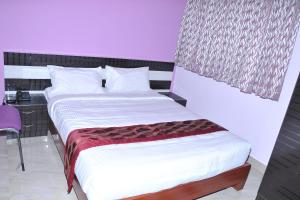 a bedroom with two beds and a purple wall at Brahma Inn in Bangalore