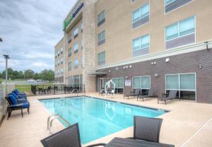 een hotelzwembad met stoelen en een gebouw bij Holiday Inn Express & Suites - Fort Mill, an IHG Hotel in Fort Mill