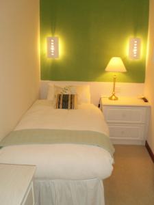 a bedroom with a white bed with a green wall at Shawlee Cottage in Airdrie